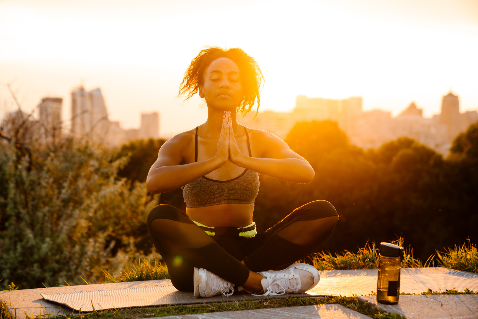 Young Black Woman in Sports Bra Meditating in Summer Park